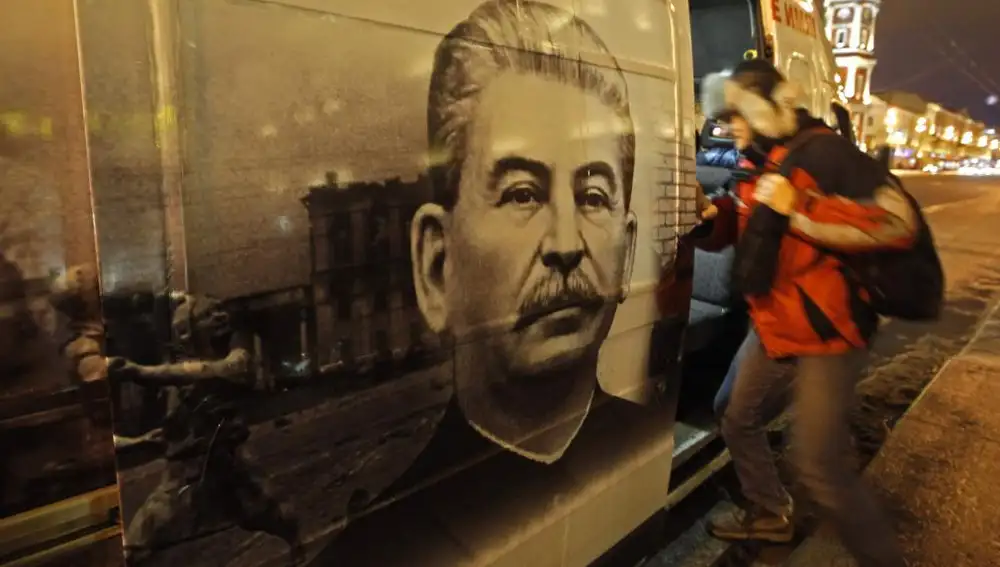 Un hombre sube a un autobús decorado con una imagen del Stalin