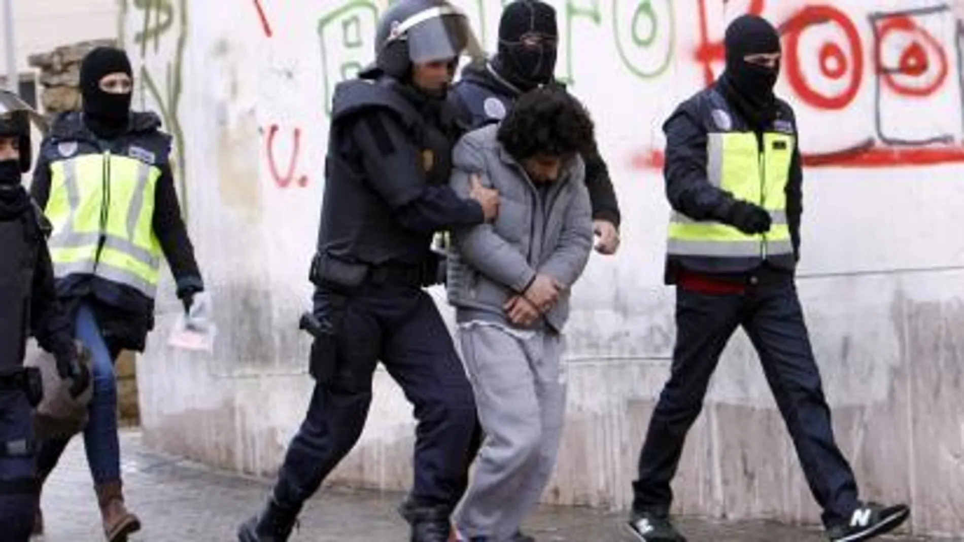 Efectivos policiales trasladan a un detenido durante una operación en Melilla contra una célula encargada del envío de yihadistas a Siria.