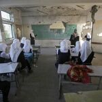 Estudiantes palestinas se sientan en un aula destruida en el primer día de colegio, después de 50 días de retraso por los conflictos