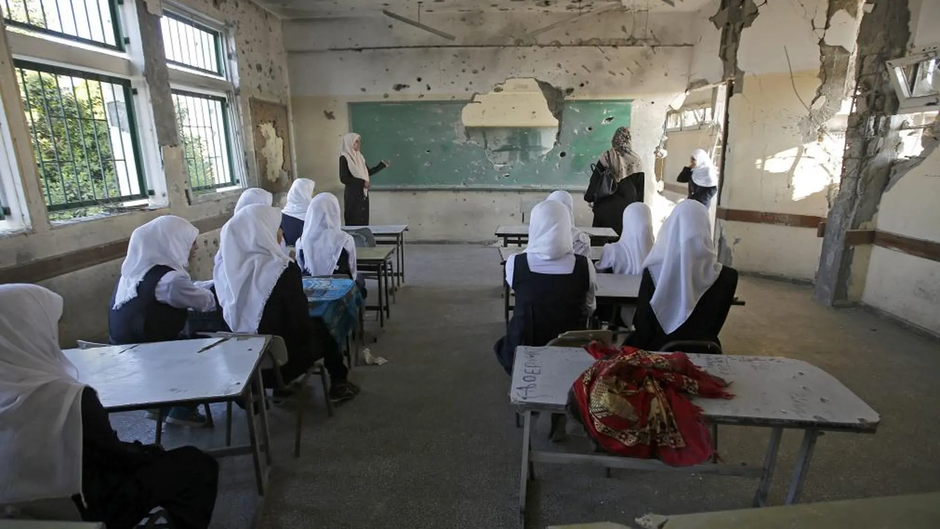 Estudiantes palestinas se sientan en un aula destruida en el primer día de colegio, después de 50 días de retraso por los conflictos