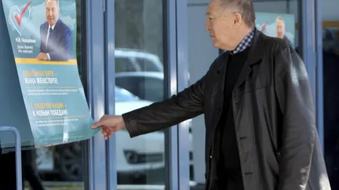 Un kazajo se detiene ante un cartel electoral del actual presidente y candidato a la reelección, Nursultán Nazarbáyev, en Astaná