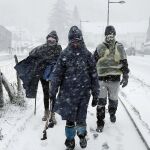 Varias personas caminan por la Colegiata de Roncesvalles donde a primeras horas de la mañana la nieve caía con insistencia.
