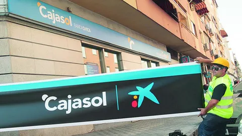 Unos operarios cambian el antiguo rótulo de Cajasol