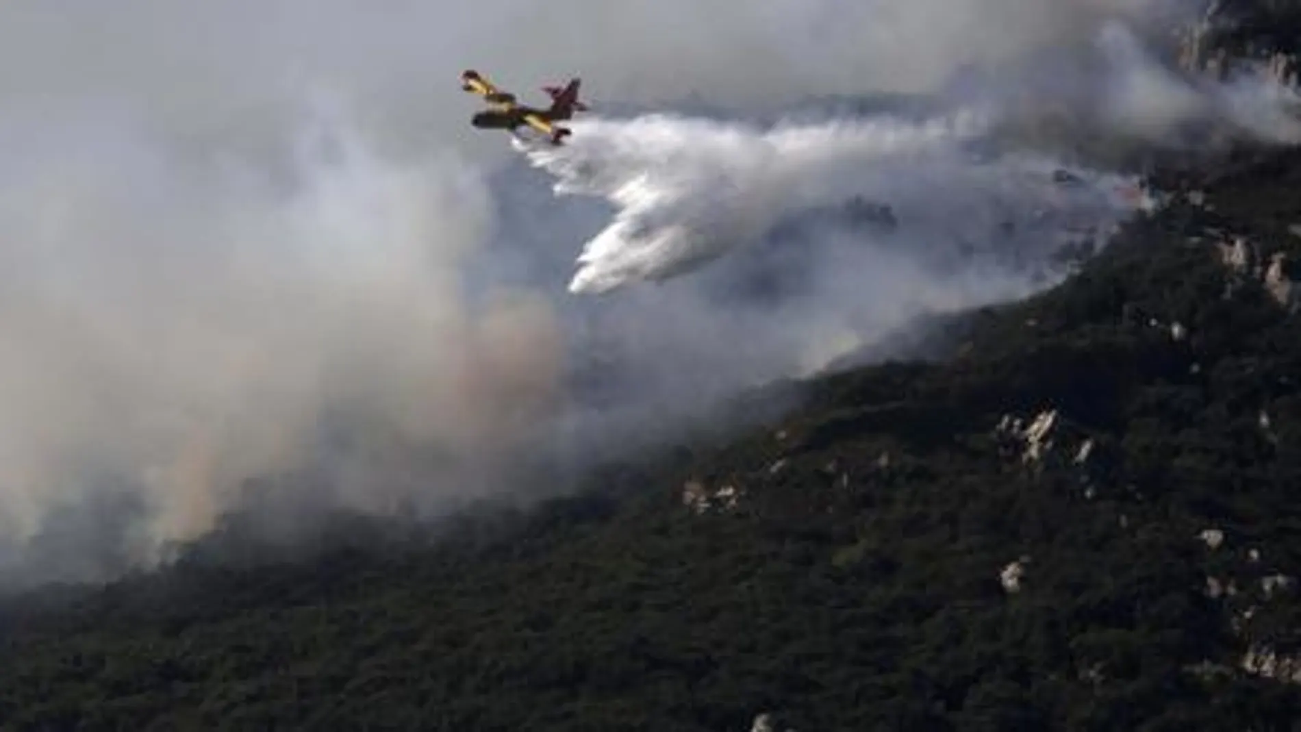 Un avión trabajando en la extinción del incendio declarado en el paraje del Río de la Miel, en Algeciras (Cádiz).