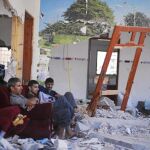 Tres palestinos descansan en lo que queda de su casa aprovechando la nueva tregua, ayer