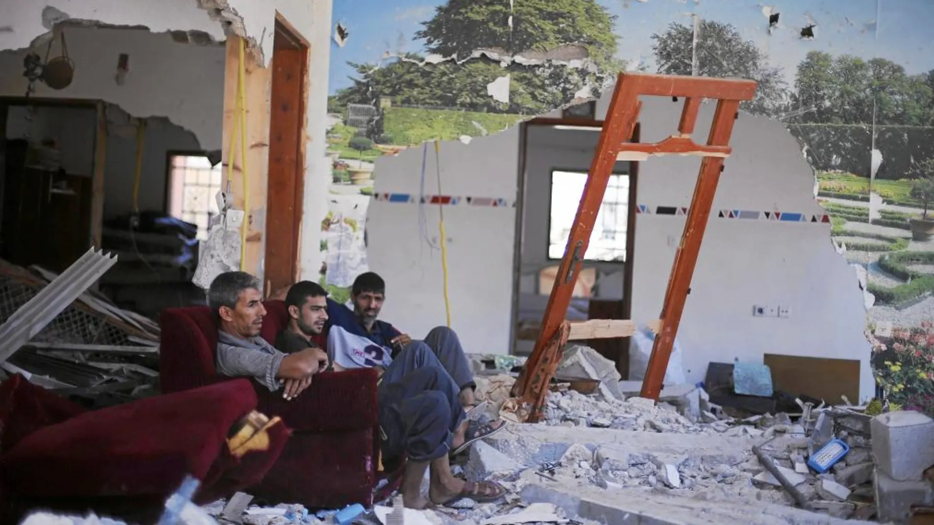 Tres palestinos descansan en lo que queda de su casa aprovechando la nueva tregua, ayer