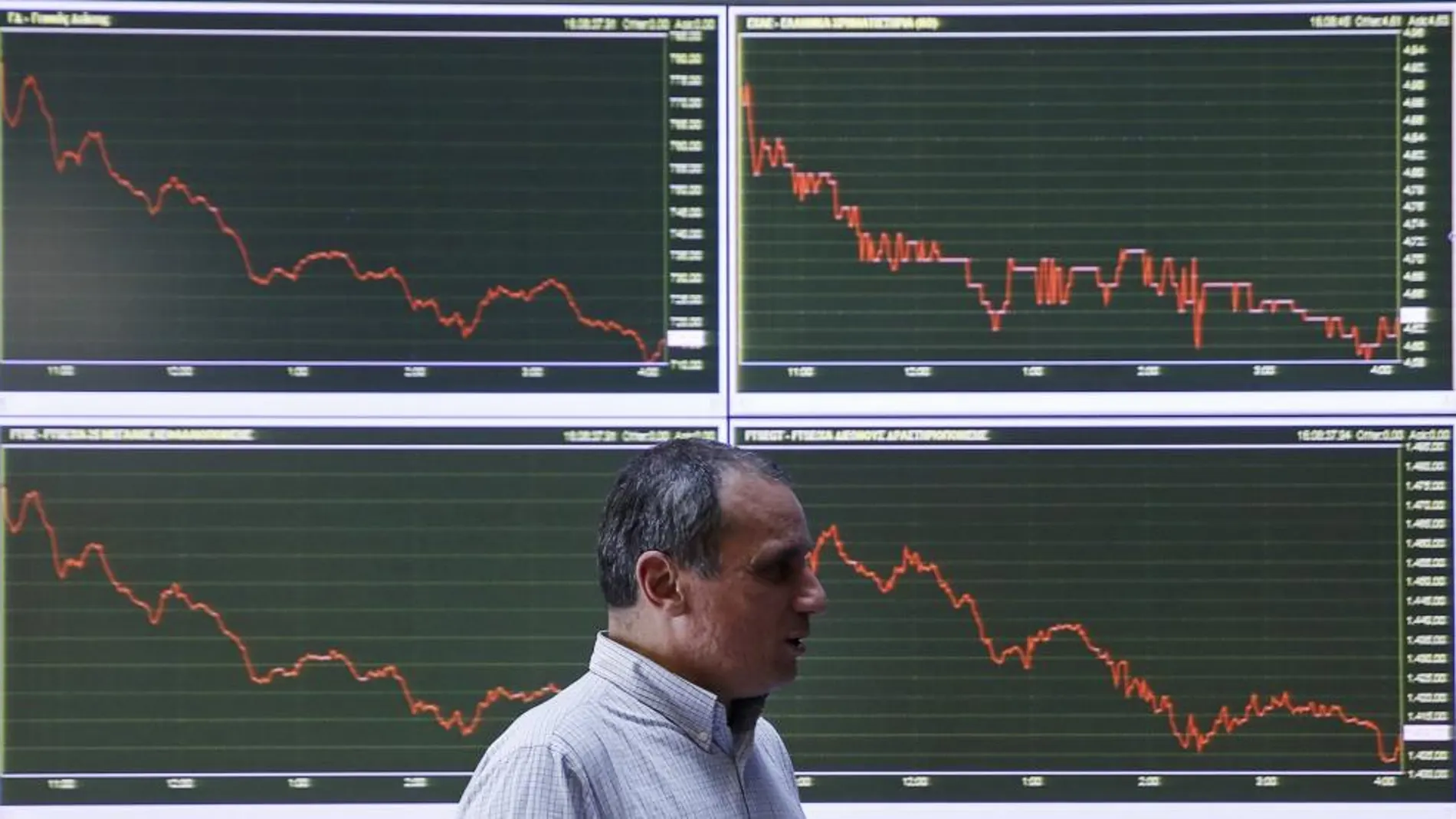 Un empleado pasa ante los gráficos de la Bolsa de Atenas.
