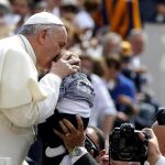 El papa Francisco besa a un niño a su llegada a la tradicional audiencia general de los miércoles.