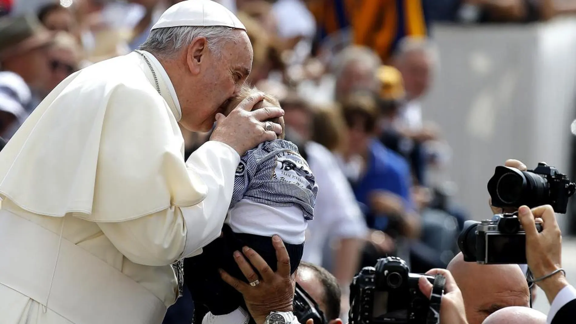El papa Francisco besa a un niño a su llegada a la tradicional audiencia general de los miércoles.