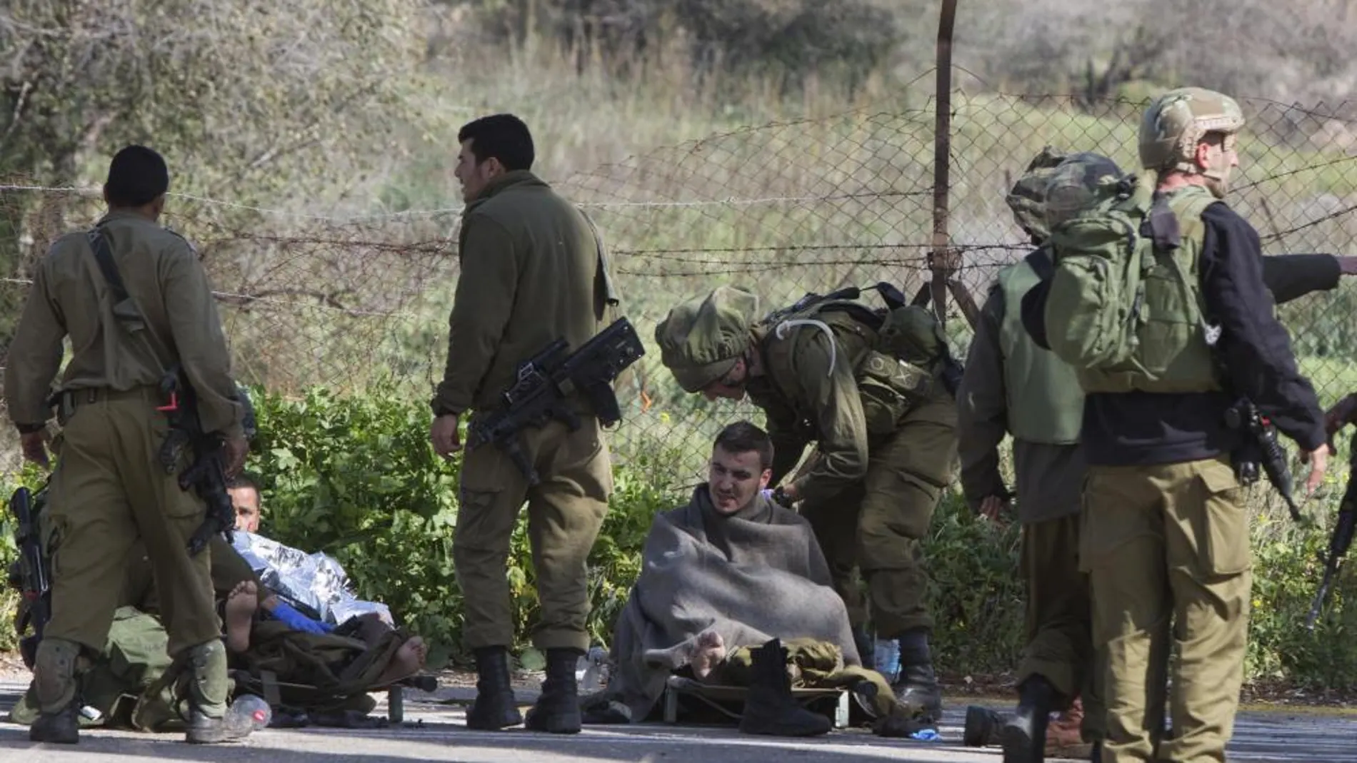 Soldados israelíes reciben atención médica de varios compañeros después de que impactara un misil antitanques en su vehículo cerca de la zona de Har Dov