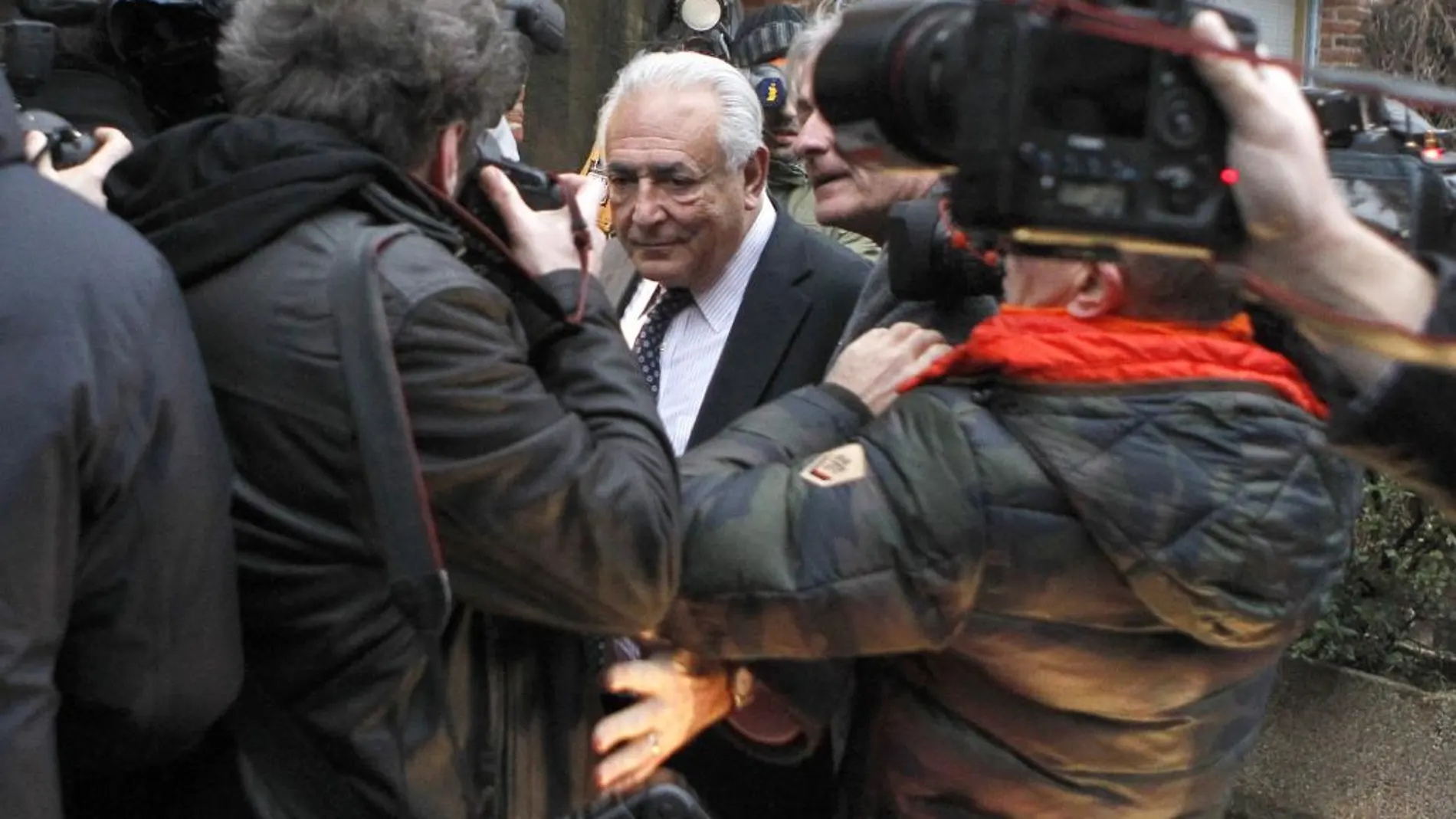 El ex director del FMI, Dominique Strauss-Kahn, rodeado de fotógrafos, a la salida de su hotel en Lille