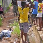 Un hombre colapsa en Monrovia (Liberia), mientras varios niños le contemplan