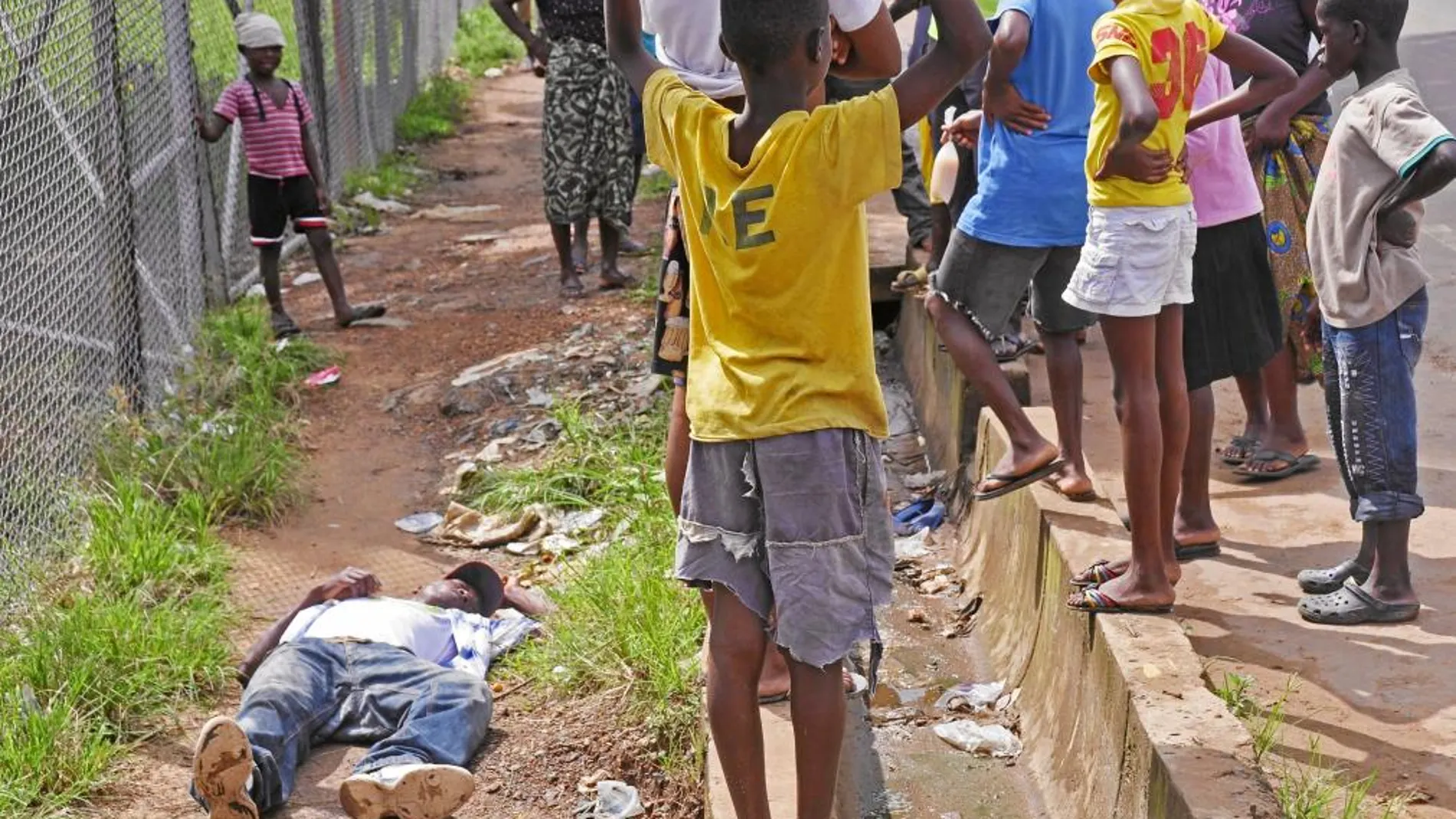 Un hombre colapsa en Monrovia (Liberia), mientras varios niños le contemplan