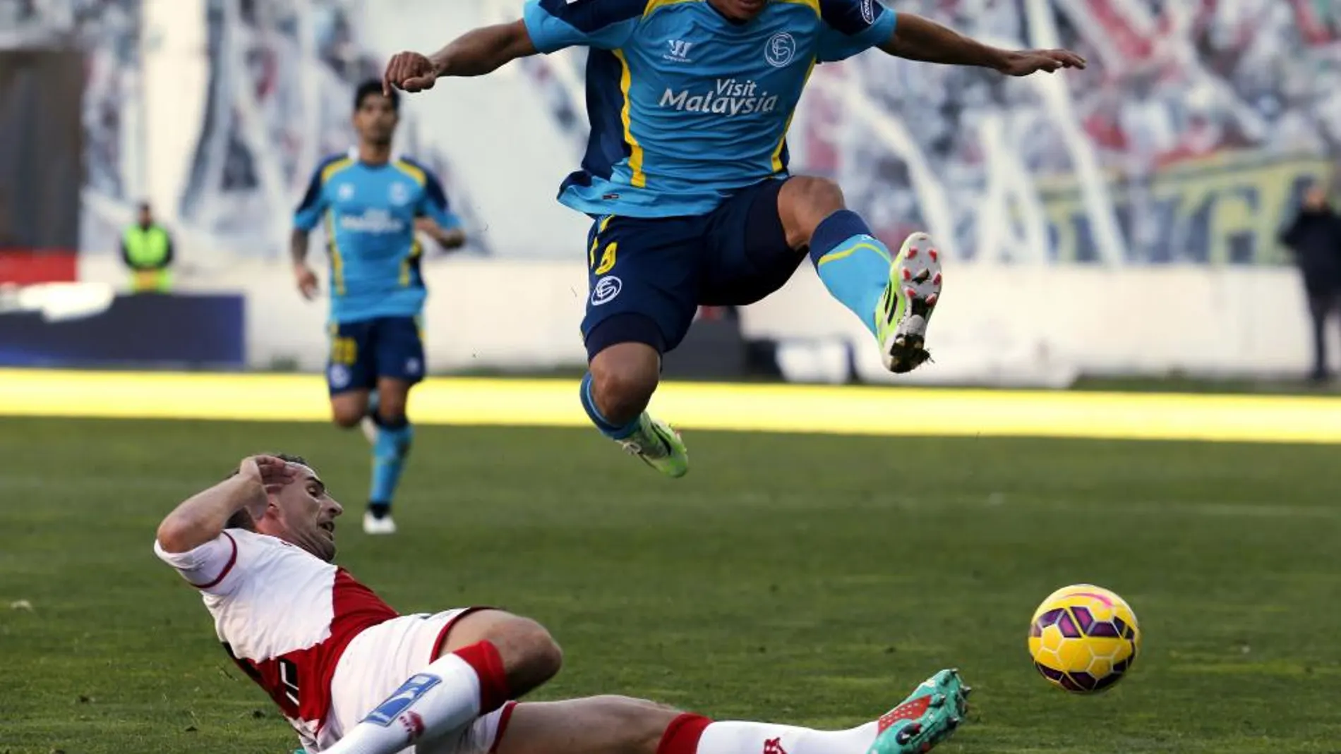 El colombiano del Sevilla Bacca y Antonio Amaya, en el suelo, del Rayo Vallecano, disputan el balón
