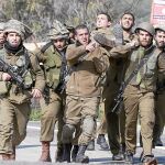 Soldados israelíes portan a un compañero herido en una camilla militar, ayer, en la frontera con Líbano