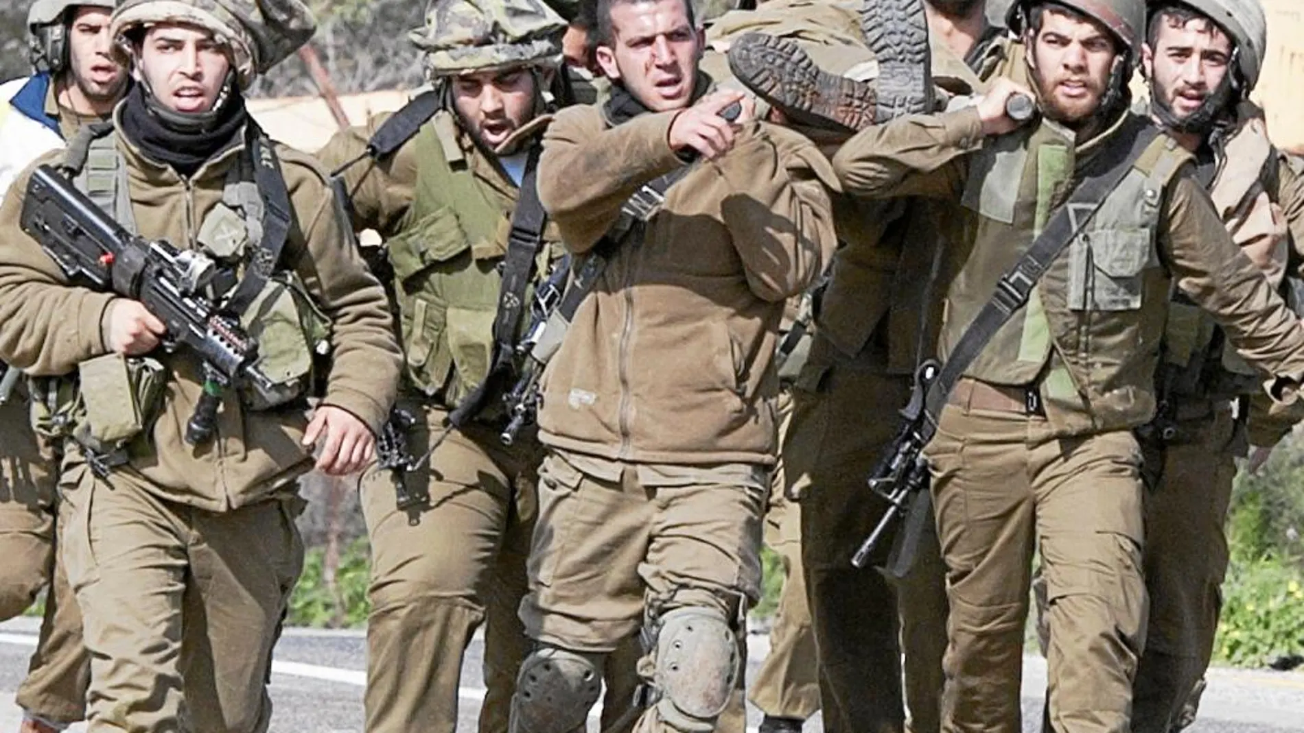 Soldados israelíes portan a un compañero herido en una camilla militar, ayer, en la frontera con Líbano