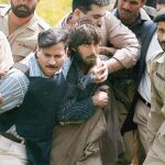 Agentes de Policía sujetan a uno de los supuestos terroristas que atentaron ayer en la academia de Lahore