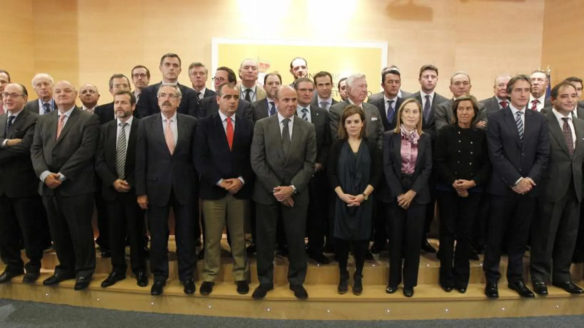 Sáenz de Santamaría (7d); la ministra de Sanidad, Ana Mato (5d); la ministra de Fomento, Ana Pastor (6d); y el ministro de Economía, Luis de Guindos (7i); posan con representantes del Banco de España, la Federación Española de Municipios y Provincias (FEMP), ONG y las entidades financieras