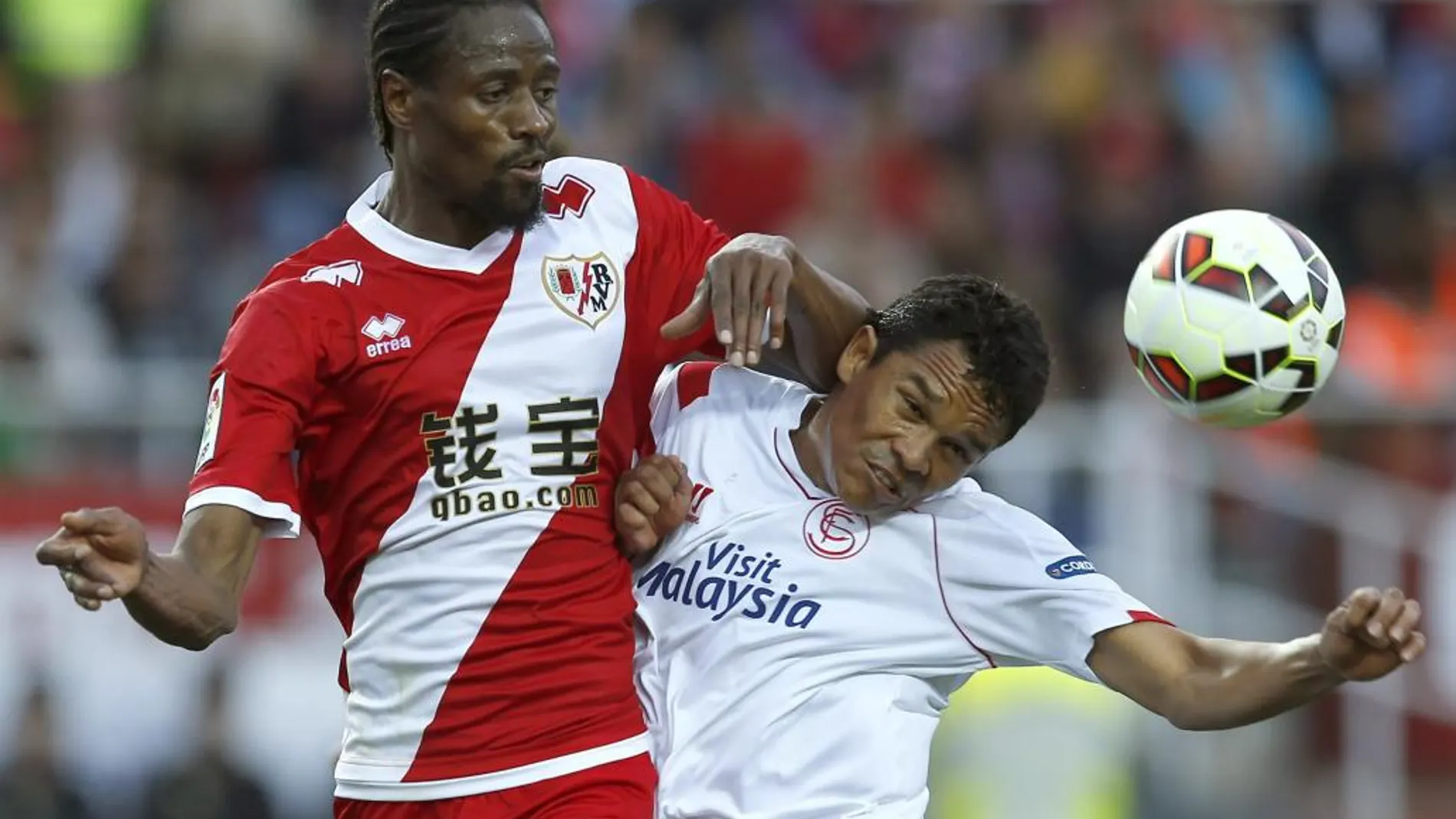El delantero colombiano del Sevilla Carlos Bacca (d) lucha el balón con el senegalés Abdoulaye Ba, del Rayo Vallecano
