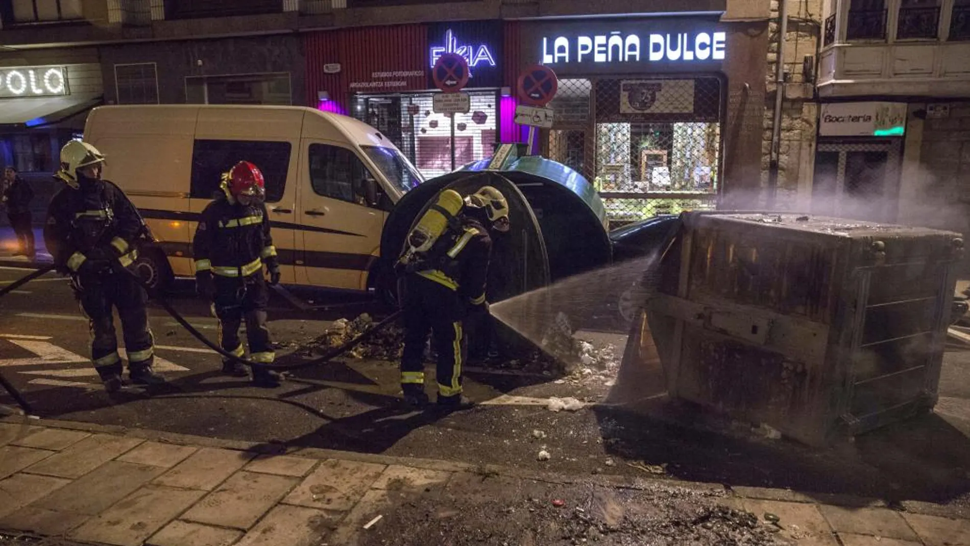 Los bomberos apagan un contenedor volcado e incendiado durante los incidentes