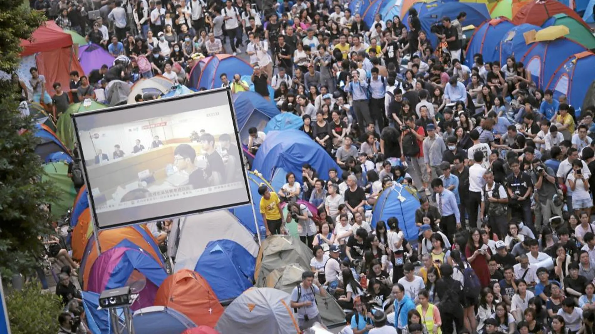 Manifestantes ven en pantallas la reunión entre las autoridades de Hong Kong y los representantes estudiantiles