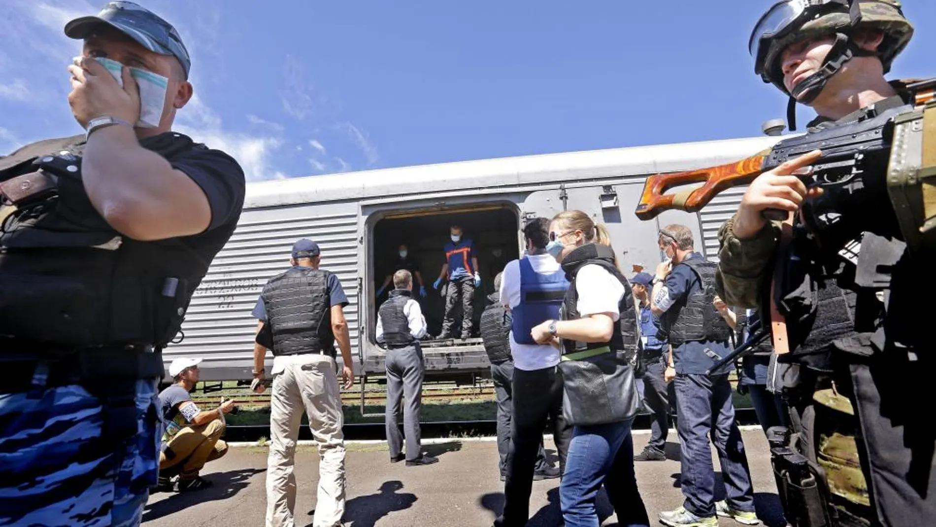 Inspectores y forenses de la OSCE (c, al fondo) revisan los cuerpos en una estación de tren de Torez
