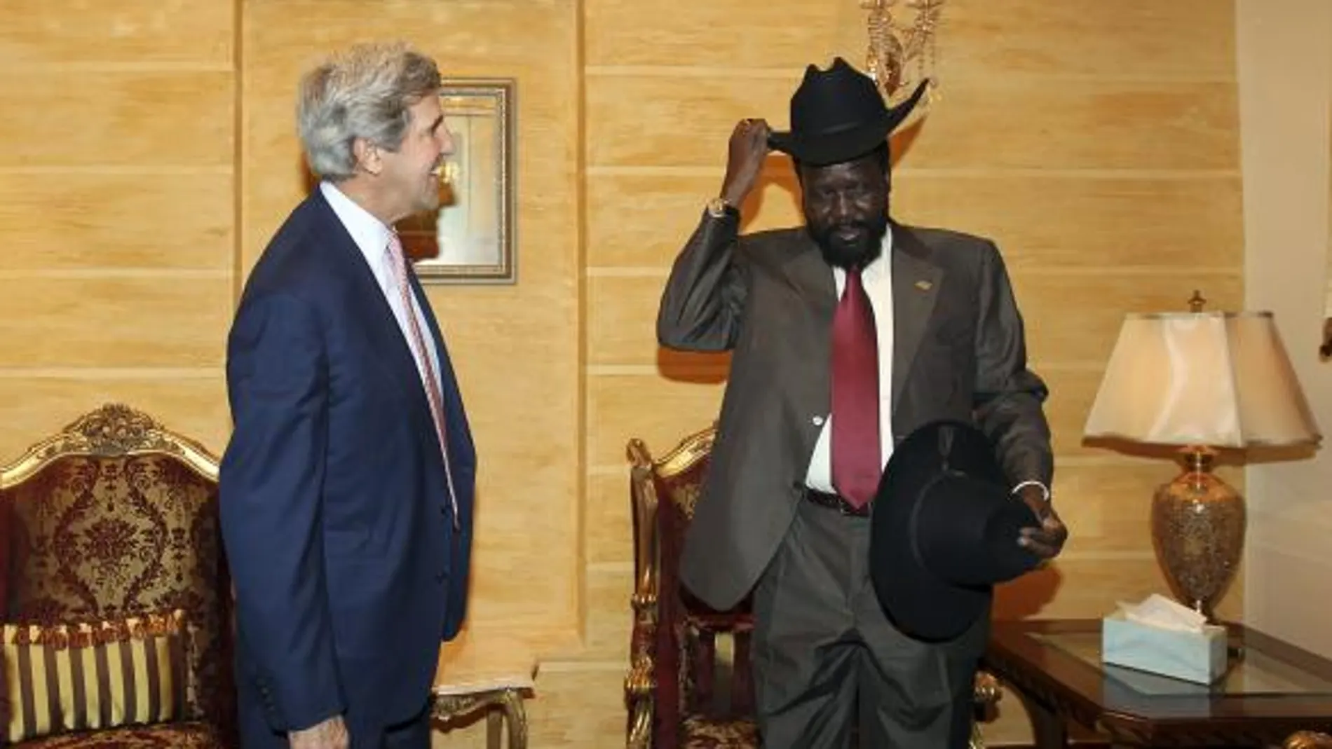 El senador estadounidense John Kerry (i) sonríe mientras el presidente del gobierno de Sudán del Sur, Salva Kiir Mayardit (d) se prueba el sombrero que le ha regalado Kerry, durante su encuentro en el palacio presidencial de Juba, en el sur de Sudán