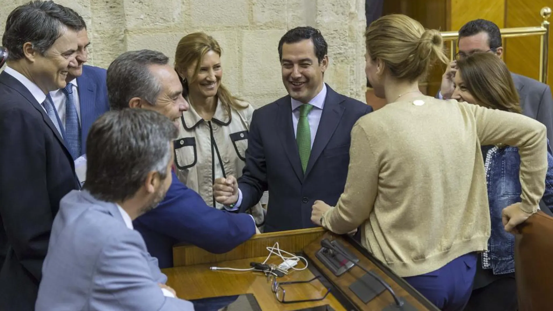 El presidente del PP andaluz, Juanma Moreno (c), habla con los diputados de su grupo antes del Pleno del Parlamento andaluz en Sevilla, en la segunda jornada del debate de investidura