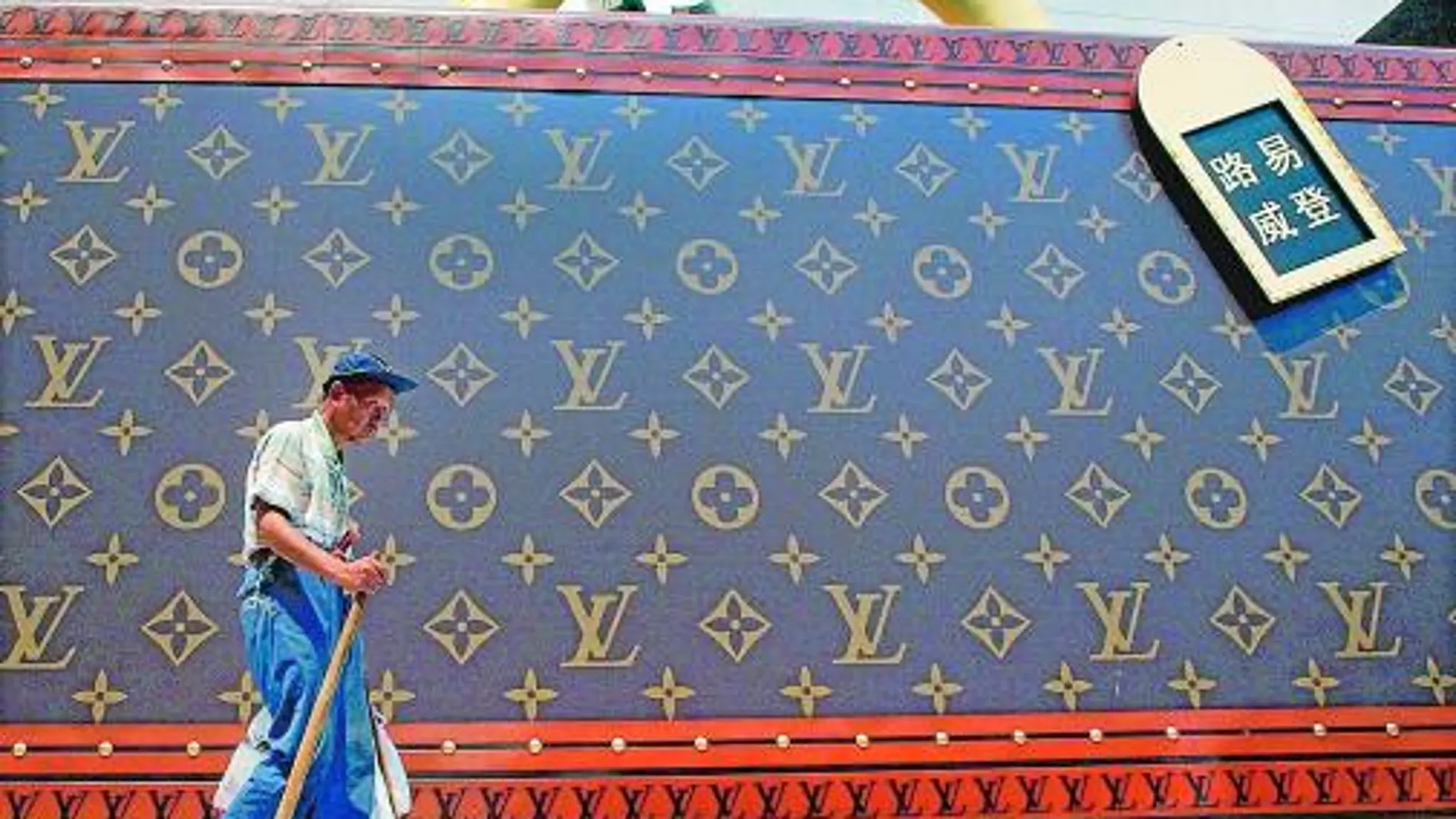 Un ciudadano chino pasa por delante de una clásica maleta de Louis Vuitton