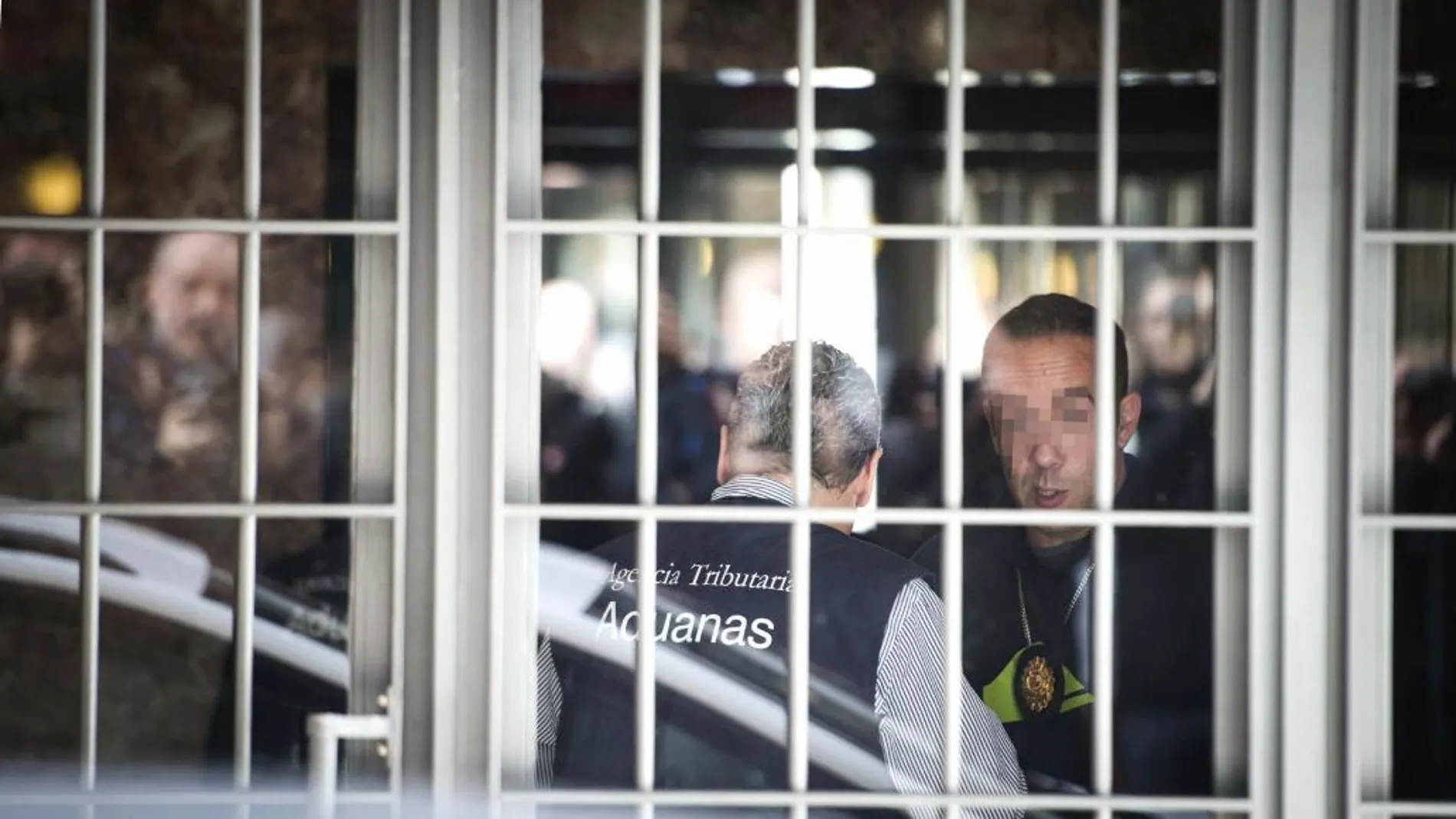 Uno de los funcionarios de la Agencia Tributaria (i) en el portal del domicilio madrileño del exvicepresidente del Gobierno y expresidente de Bankia, Rodrigo Rato.