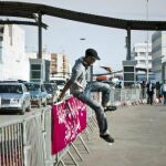 Un joven marroquí salta la valla que divide el acceso de entrada y salida del puesto fronterizo de España y Marruecos