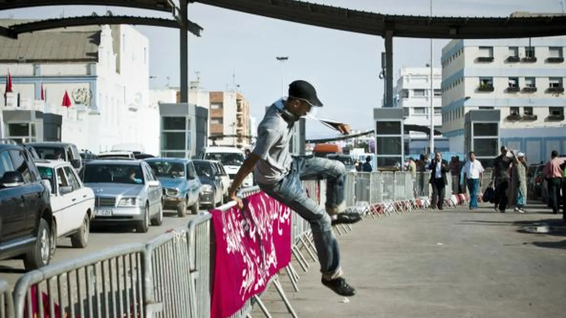 Un joven marroquí salta la valla que divide el acceso de entrada y salida del puesto fronterizo de España y Marruecos