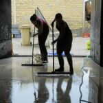 Dos mujeres se afanan en achicar agua del garaje de su vivienda en Aguilar de la Frontera, uno de los municipios más afectados junto a Bujalance