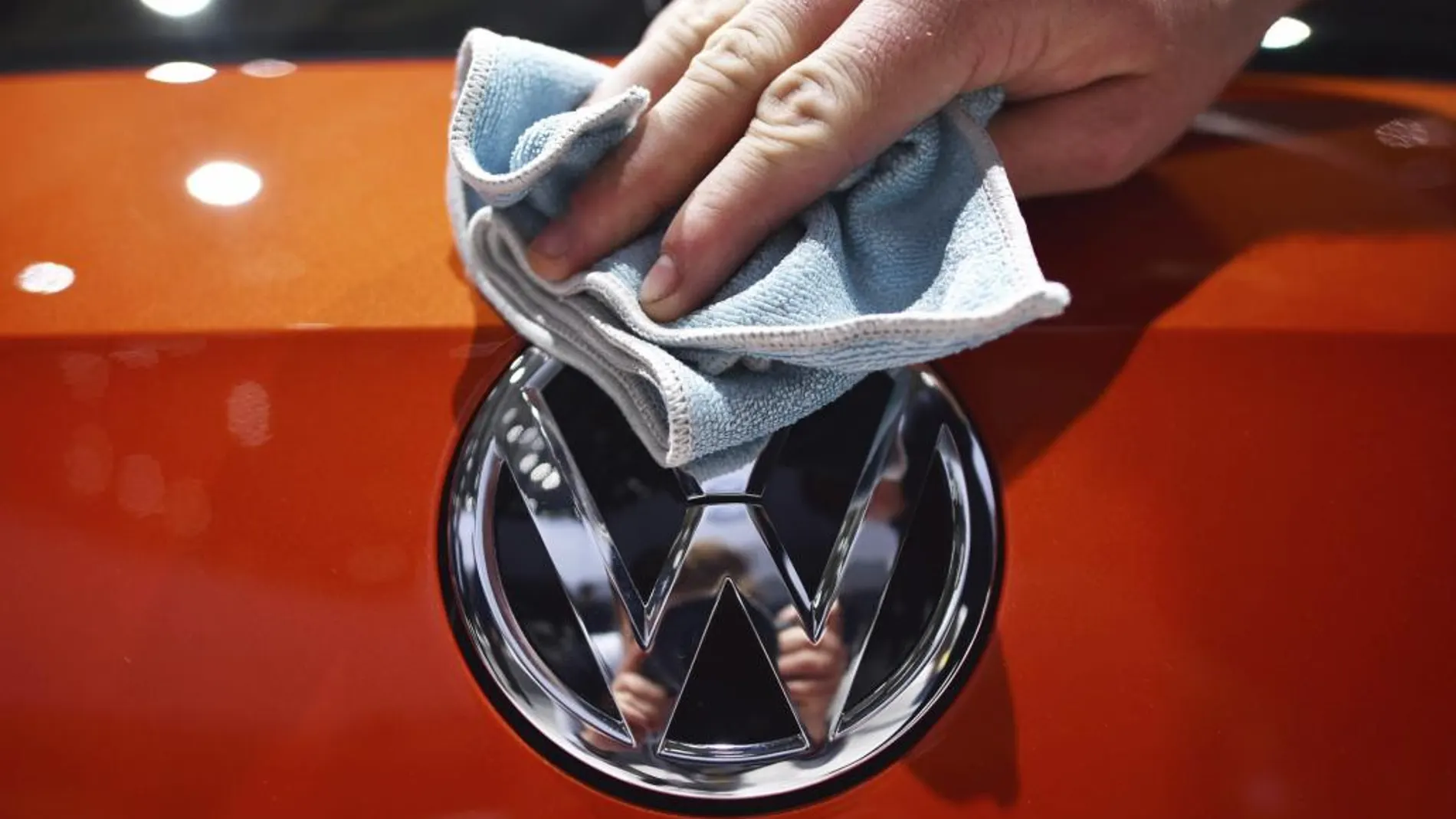 Una persona abrillanta el logotipo de Volkswagen durante una junta de accionistas celebrada en un recinto ferial de Hanover (Alemania)