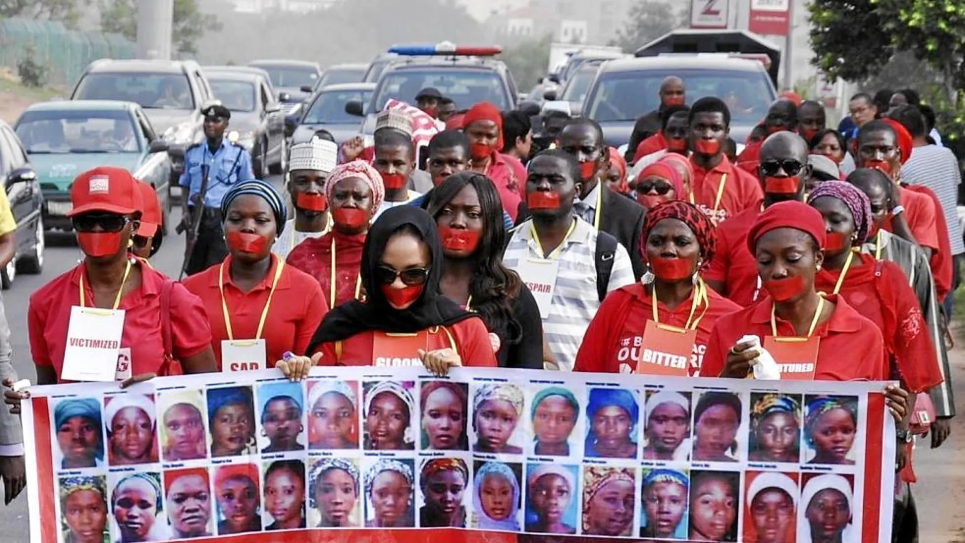 Un grupo de manifestantes marcha en Abuja (Nigeria) con la boca tapada en protesta por el secuestro hace un año de 300 adolescentes en Chibok