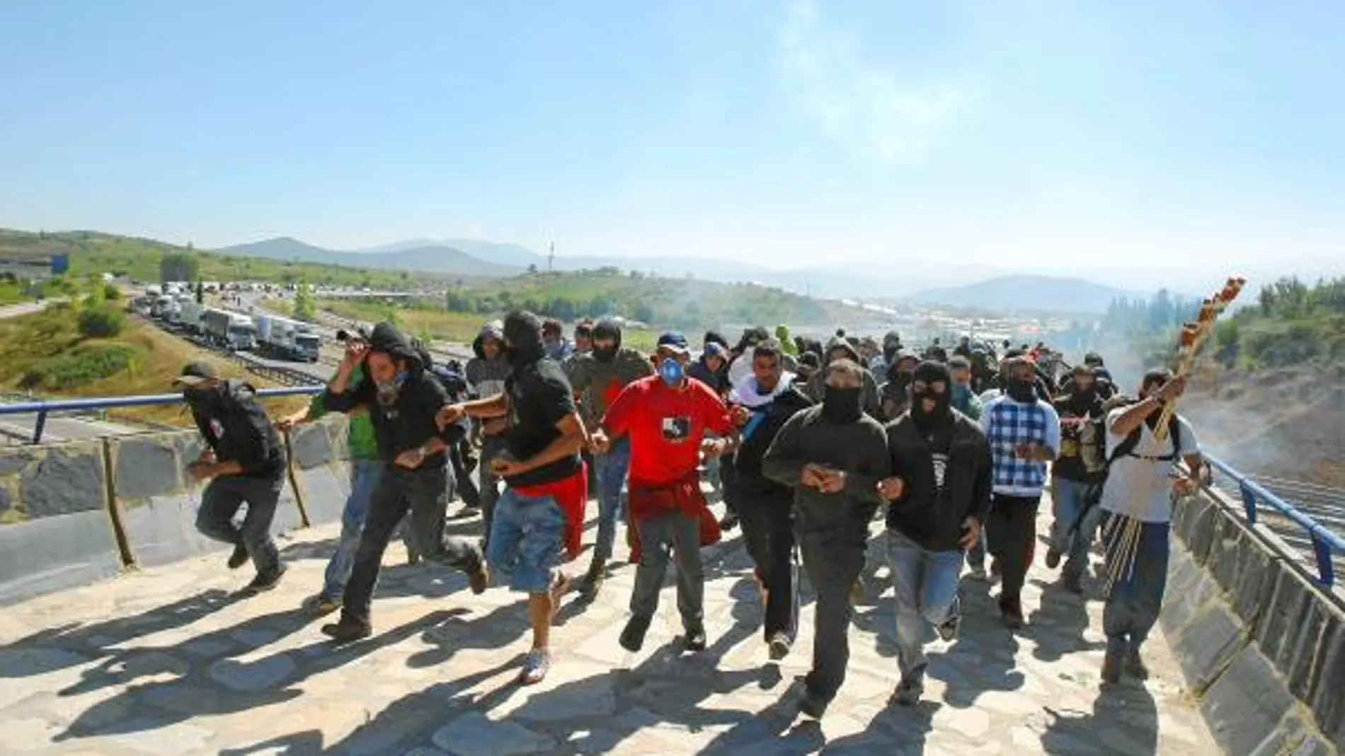Los mineros corren delante de los antidisturbios, tras cortar la A-6 en Camponaraya (León)