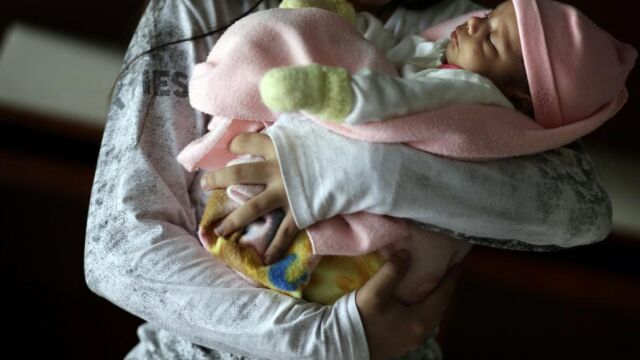 Una niña de 13 años sostiene a su bebé en brazos