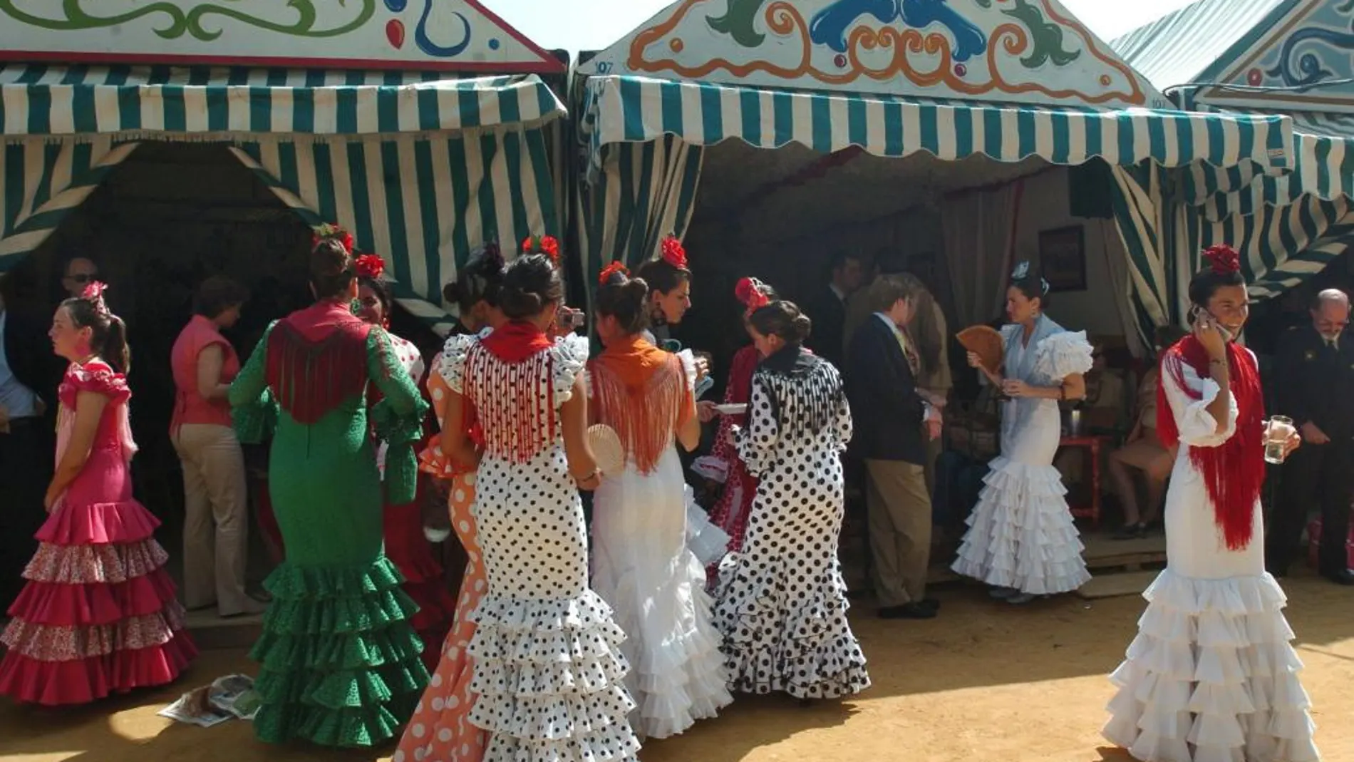 Mujeres vestidas de flamenca a las puertas de varias casetas