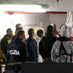 Policías guían a los inmigrantes supervivientes de los recientes naufragios sobre el buque de la guardia costera "Bruno Gregoretti"en el puerto de Catania en Sicilia.