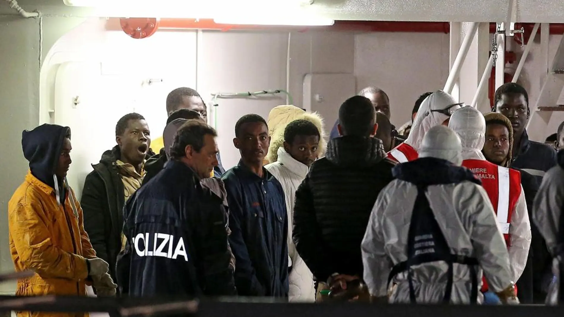 Policías guían a los inmigrantes supervivientes de los recientes naufragios sobre el buque de la guardia costera "Bruno Gregoretti"en el puerto de Catania en Sicilia.