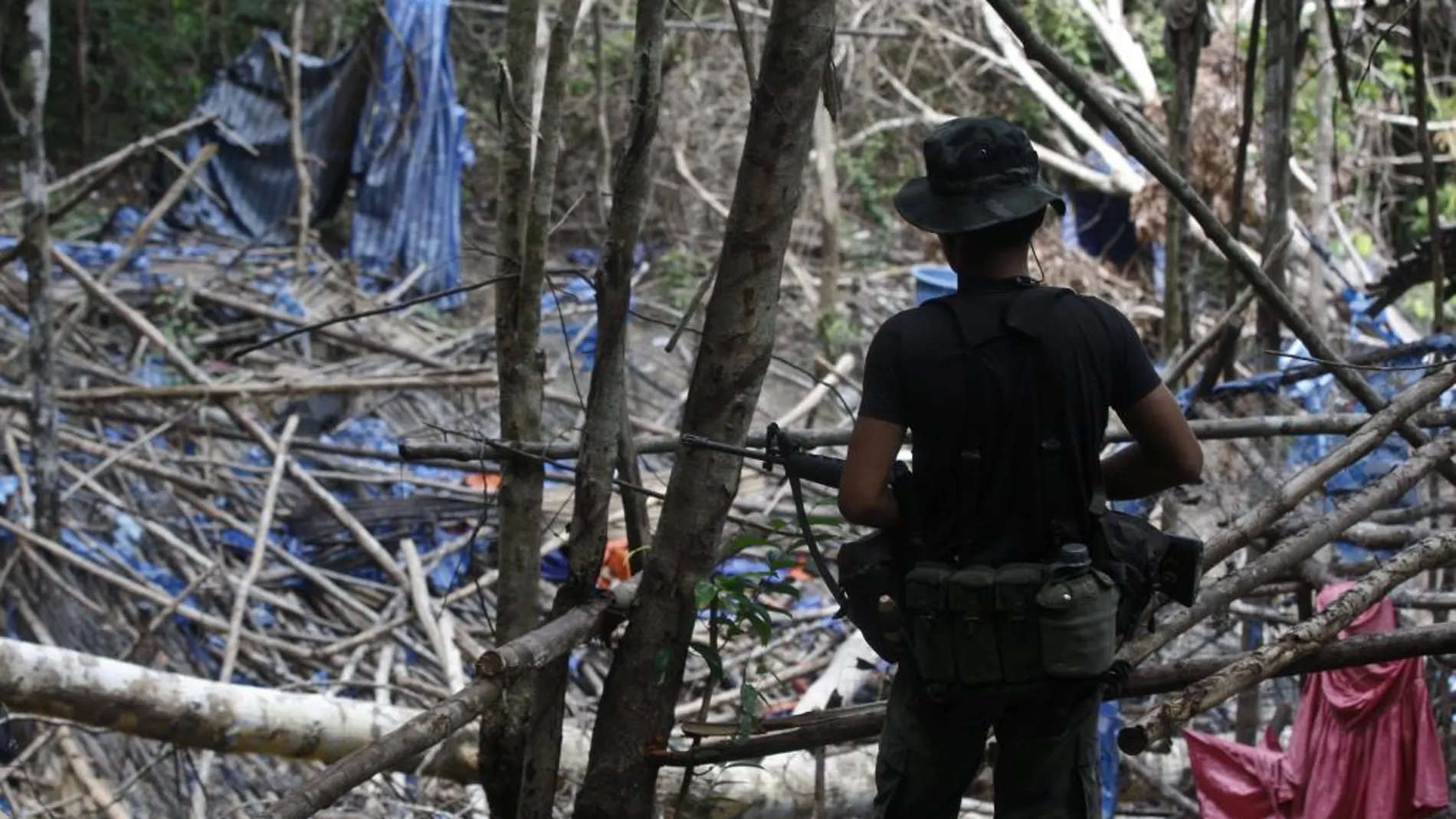 Un policía malasio vigila un campamento abandonado tras descubrirse en el lugar varias tumbas, en las colinas Wang Burma en Wang Kelian, Perlis (Malasia)