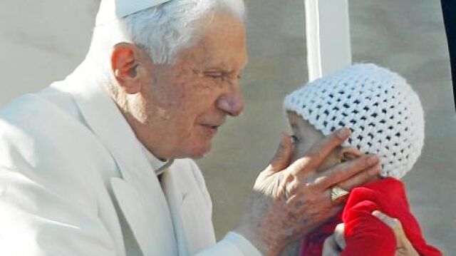 El papa Benedicto XVI saluda a un bebé y a los devotos congregados en la plaza de San Pedro del Vaticano durante la audiencia pública de los miércoles