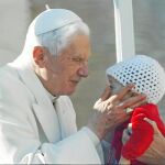 El papa Benedicto XVI saluda a un bebé y a los devotos congregados en la plaza de San Pedro del Vaticano durante la audiencia pública de los miércoles
