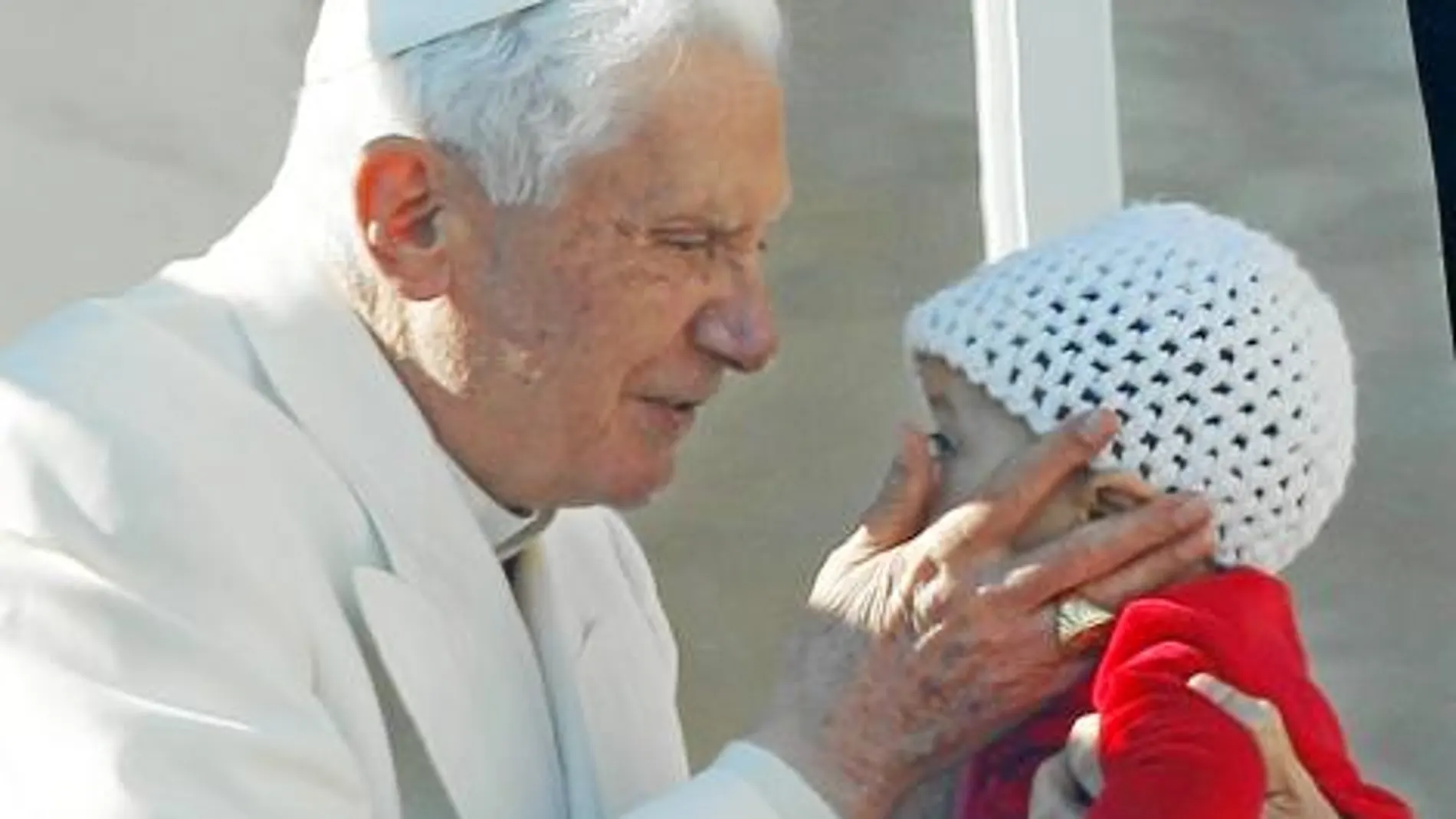 El papa Benedicto XVI saluda a un bebé y a los devotos congregados en la plaza de San Pedro del Vaticano durante la audiencia pública de los miércoles