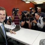 El presidente del PP, Mariano Rajoy (i), es fotografíado por los medios de comunicación momentos antes de ofrecer una conferencia, en San Lorenzo de El Escorial