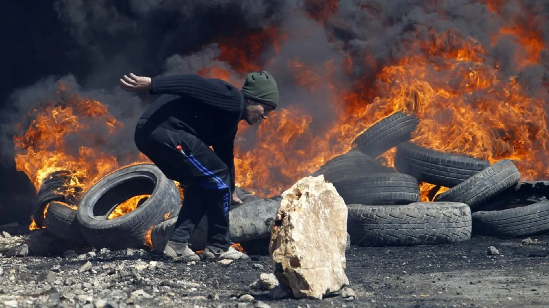 Un manifestante palestino hace una barricada durante los enfrentamientos con soldados israelíes tras una protesta contra el asentamiento israelí de Qadomem