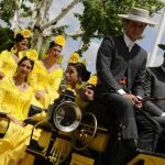 Un coche de caballos con jóvenes vestidas de flamenca pasean por la Feria de Abril