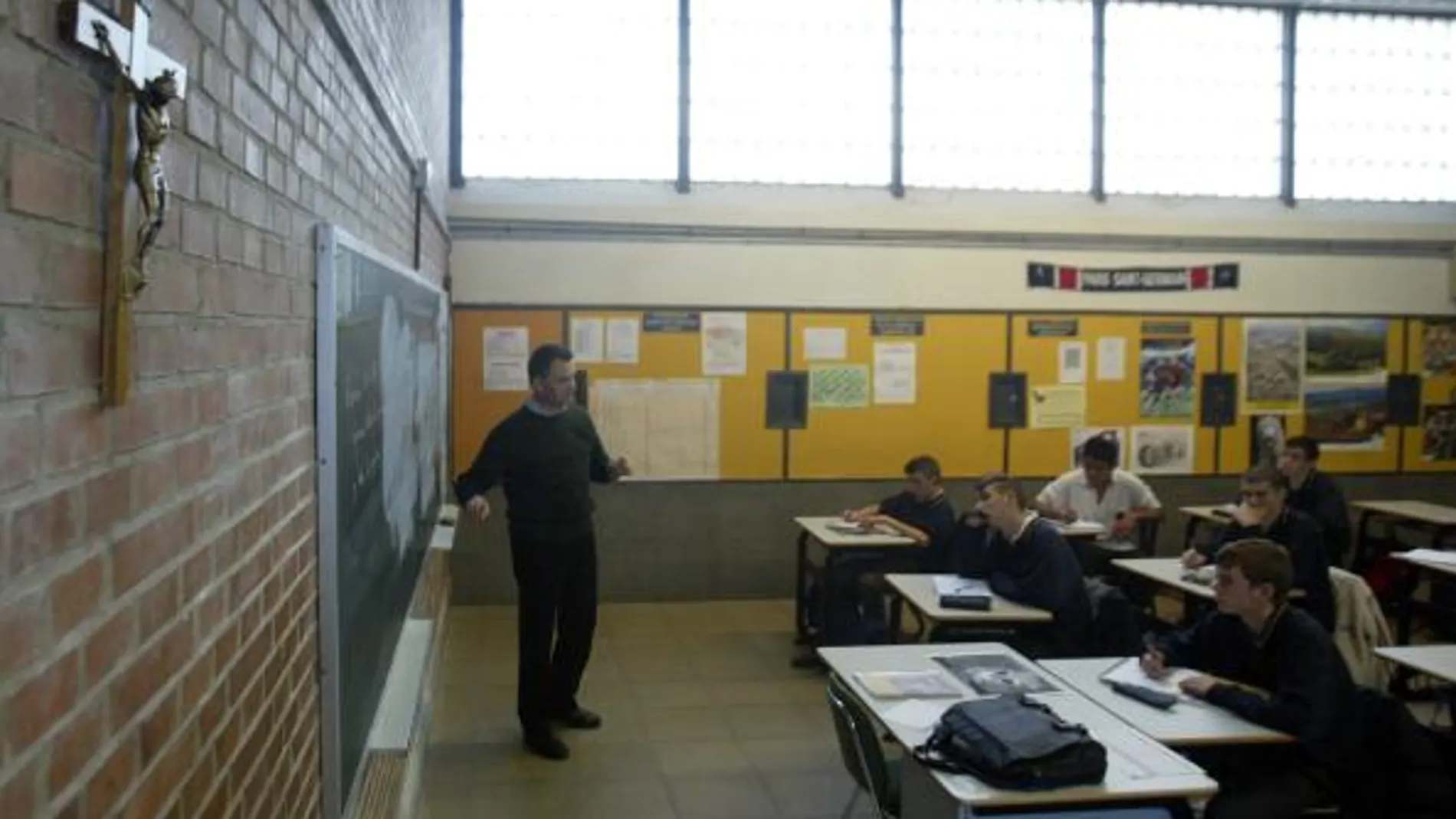 Un profesor da clase en un colegio concertado con el crucifijo en la pared