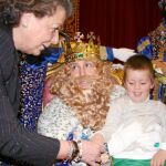 REGALOS: Un niño recibe un regalo del rey Gaspar acompañado por la alcaldesa de Valencia, Rita Barberá.