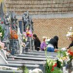 Una familia al completo, colocando varios ramos de flores junto a la tumba de un allegado en el cementerio de Nuestro Padre Jesús de Espinardo
